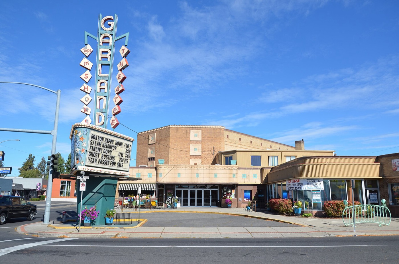 The Garland Theater marquee on a sunny day, with storefronts beside it displaying large For Lease signs in their windows. The 900 block of West Garland Avenue, Spokane, photographed in 2016.